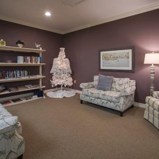 A cozy living room with patterned sofas and a well-lit bookshelf.