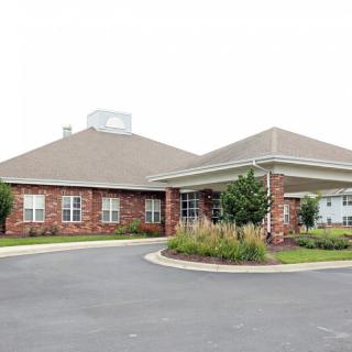 A brick building with a covered entrance and landscaped surroundings.