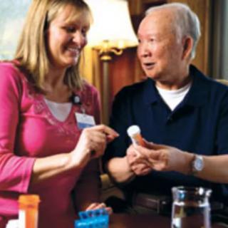A caregiver assisting an elderly man with medication at home.