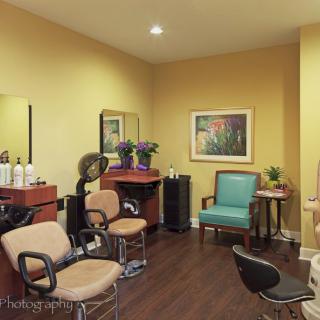 A cozy salon interior featuring multiple styling stations, mirrors, and a comfortable seating area.