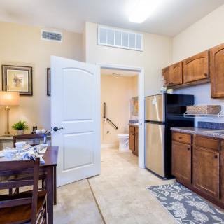 A cozy apartment kitchen with wooden cabinets, a dining table, and modern appliances.