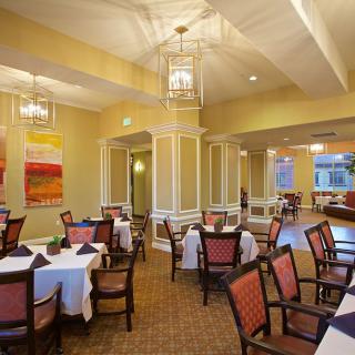 An elegant dining room with neatly arranged tables and chairs, featuring warm lighting and tasteful decor.