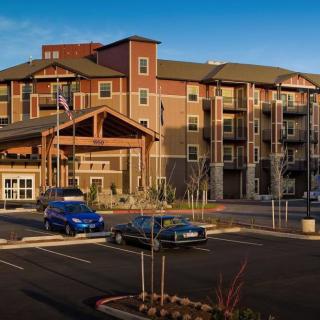 A modern apartment complex with a parking lot and cars at sunset.