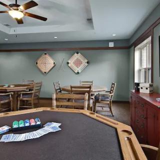 A spacious game room featuring a poker table with seating and a ceiling fan, perfect for gatherings.
