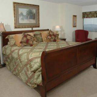 A spacious bedroom with a large wooden bed, stylish bedding, and classic decor.