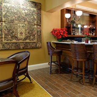 A cozy bar area featuring elegant wooden furniture, an intricate rug, and decorative accents.