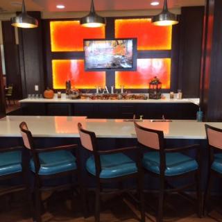 A modern bar area with blue seats and a wall-mounted television.