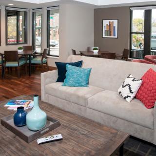 A modern living room with a beige sofa, vibrant cushions, and a wooden coffee table featuring decorative vases.