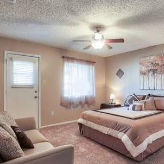 A cozy bedroom featuring a bed, ceiling fan, and soft lighting.
