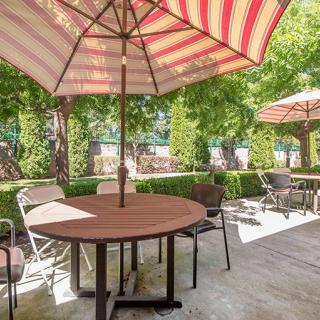 A cozy outdoor patio area with tables and chairs under striped umbrellas.
