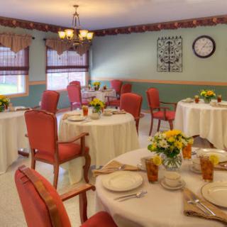 A cozy dining room featuring well-set tables with floral centerpieces, ready for a meal.
