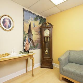 A cozy waiting room featuring a grandfather clock, wall art, and comfortable seating.