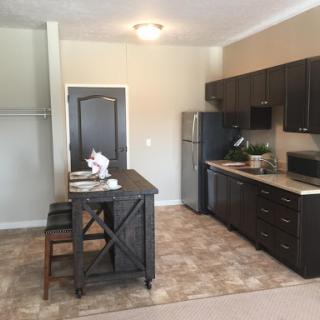 A modern kitchen area featuring a dining table, sleek cabinetry, and stainless steel appliances.