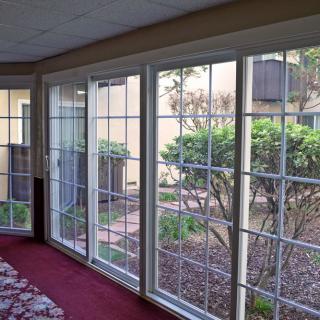 A bright sunroom with large glass windows offering a view of a garden.