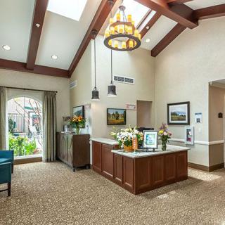 A well-lit lobby area with a reception desk, decorative lighting, and artwork on the walls.