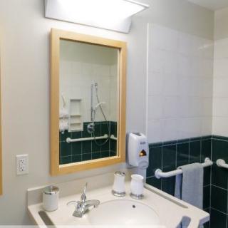 A well-lit bathroom with a wooden-framed mirror and a sink area.