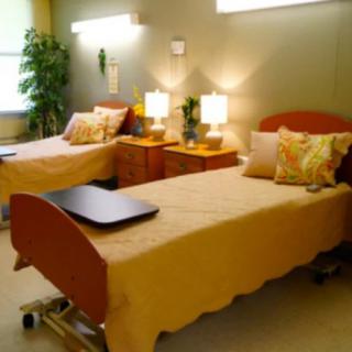 A well-lit hospital room with two beds and bedside tables.