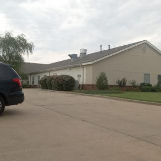 A suburban house with a vehicle parked on the driveway under a cloudy sky.