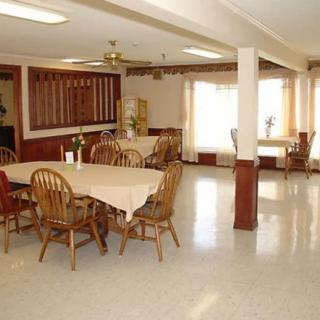 A spacious dining area with wooden chairs and tables, featuring bright natural lighting.