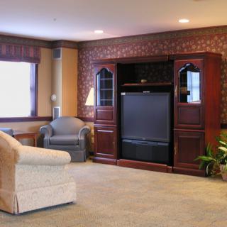 A cozy living room with comfortable seating and a large TV unit against a brick accent wall.
