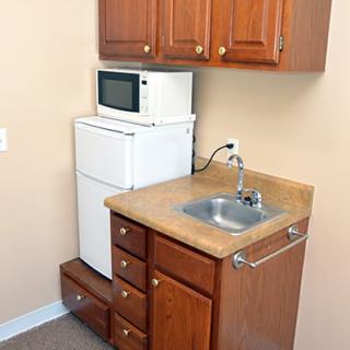 A compact kitchen setup with a sink, microwave, and refrigerator.