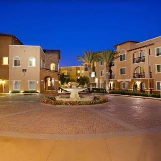 A beautifully lit apartment courtyard with a central fountain at night.