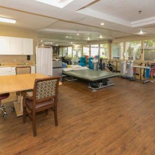 A spacious therapy room equipped with exercise machines and a table with chairs.