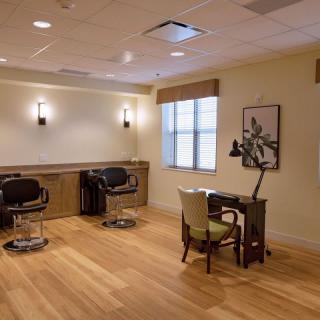 A well-lit salon interior with chairs and a desk on a wooden floor.