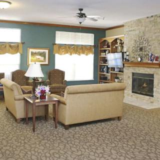 A cozy living room with sofas, chairs, and a fireplace, featuring a bookshelf and decorative elements.