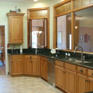 A spacious kitchen featuring wooden cabinets and a dark countertop with a double sink.