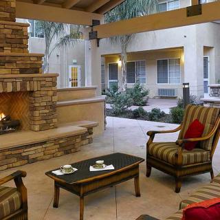 A cozy outdoor patio with comfortable seating and a fireplace in a courtyard setting.