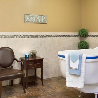 A cozy bathroom with a classic bathtub, elegant chair, and side table.
