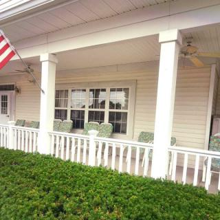 A charming porch with white columns and an American flag, featuring comfortable seating.