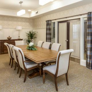 A well-decorated dining room with a large wooden table and upholstered chairs, featuring tasteful decor and potted plants.
