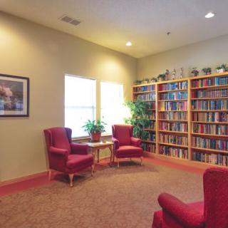 A cozy library with red chairs and a large bookshelf.