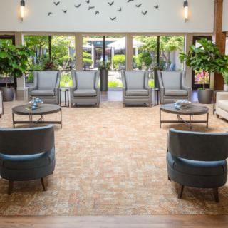 A spacious lobby with elegant seating, large windows, and lush plants.