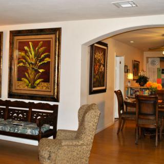 A beautifully decorated living and dining area featuring elegant furniture, framed artwork, and warm lighting.