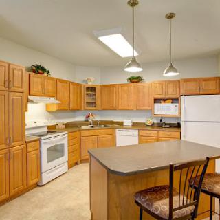A spacious and well-lit kitchen featuring wooden cabinetry, modern appliances, and a central island.