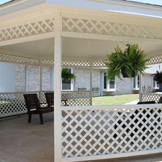 A spacious gazebo with lattice walls, hanging plants, and outdoor seating.