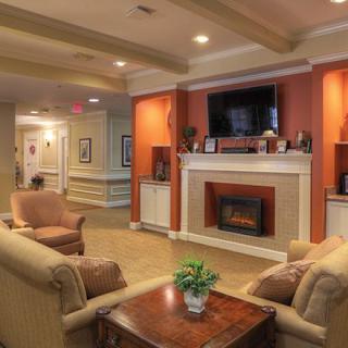 A cozy living room featuring a fireplace and seating area, decorated with warm tones and stylish furnishings.