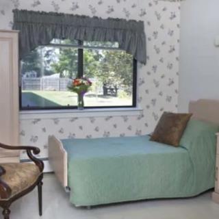 A cozy bedroom with a single bed, decorated with floral patterns and a window view.