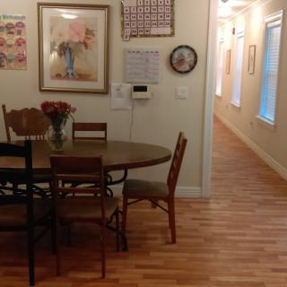 A cozy dining area with a wooden table, chairs, and decorative artwork on the walls, leading to a hallway.