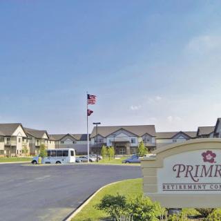 Entrance to a senior living community with a flag flying in the foreground.
