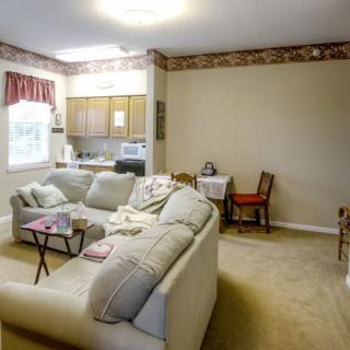 A cozy living room features a comfortable sofa, small dining area, and a view into the kitchen.