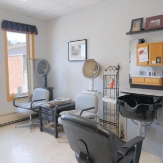 A cozy hair salon with seating, hair dryers, and a mirror station.