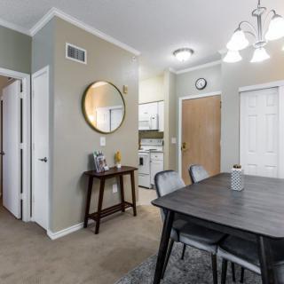 A modern dining room with a dark wooden table, upholstered chairs, and a round wall mirror.