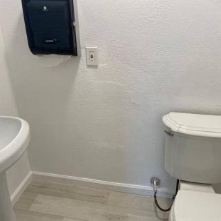 A simple bathroom with a toilet, sink, and paper towel dispenser.