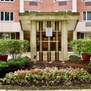 The entrance of a building with well-maintained landscaping and greenery.