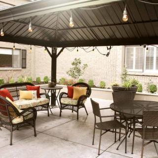 A cozy outdoor patio with a gazebo, featuring comfortable seating and ambient lighting.