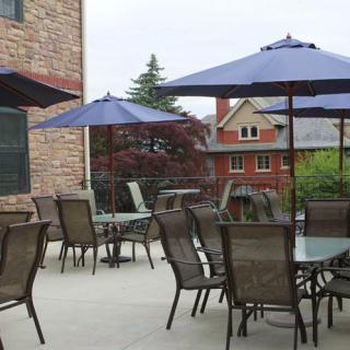 A patio with tables, chairs, and umbrellas next to a brick building.